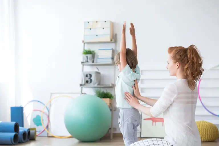 specjalistka przeprowadza zajęcia ruchowe z dzieckiem na sali do rehabilitacji